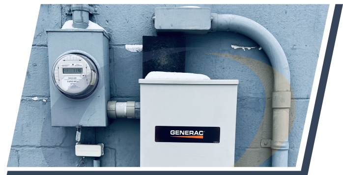 An electrical box in a white metal box on the side of a wall with a gauge in a grey box connected to it with grey tubes